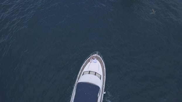 Aerial top view of a luxury white yacht and relaxing people. Clip. Concept of summer vacation, beautiful sail boat cruising in deep blue Aegean sea.