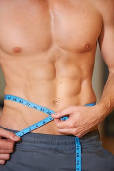 Man, measuring tape and abdomen muscle in closeup for growth development or check results in gym. Person, bodybuilder or review progress in training, strong or stomach for wellness, health or fitness