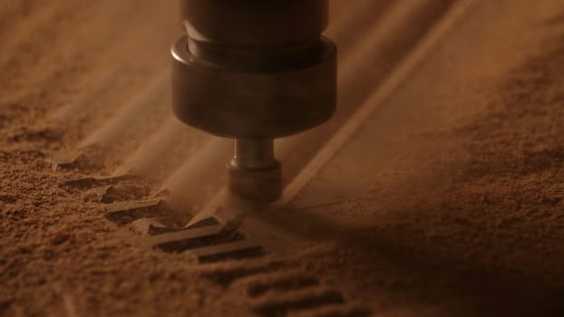 Carving geometric pattern on wooden sheet with small drill at woodwork factory, macro view. Creative. Wood lathe machine processes detail creating sawdust.