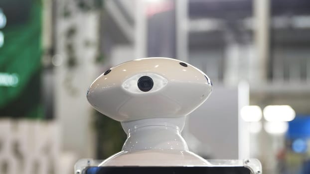 Close up of the moving humanoid robot with a camera on his head. Media. New technological robot moving at the exhibitional center, technologies of the future.