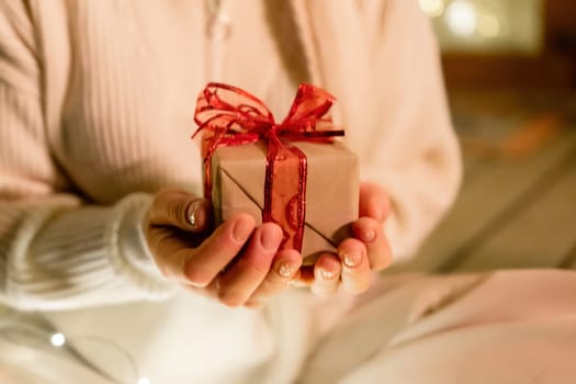 gift woman hands. Close up shot of female hands holding a small gift wrapped with red ribbon. Small gift in the hands of a woman.