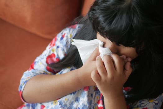 Sick child with flu blow nose with napkin.