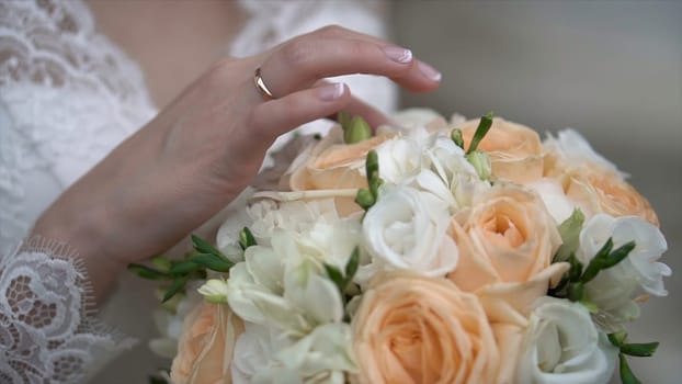 Nice wedding bouquet in bride's hand. Clip. Fiancee in a beautiful white dress holding a beautiful bouquet of wedding flowers made of tender roses in hand