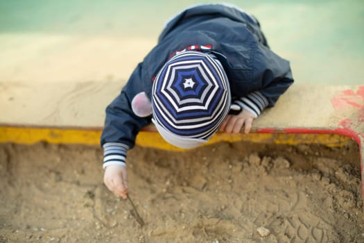 Child in sandbox. Preschooler on playground.