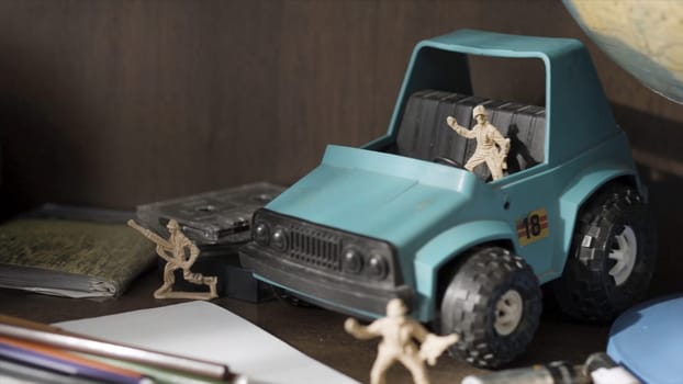Toy soldier. Plastic Green Tracked Army Vehicle on a battlefield. Miniature toy soldiers.