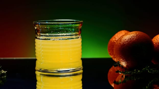 Orange alcohol cocktail in a glass on colorful wall background. Stock clip. Cold refreshing drink and a bar counter with orange fruits.