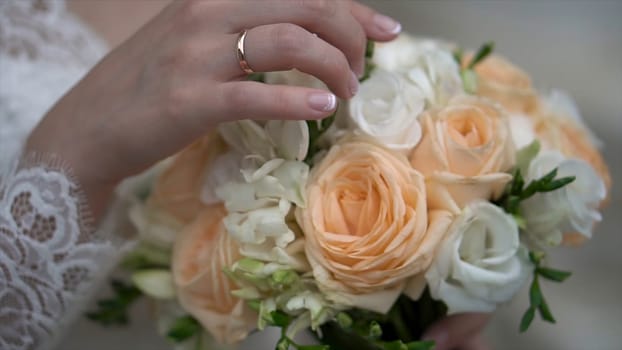 Nice wedding bouquet in bride's hand. Clip. Fiancee in a beautiful white dress holding a beautiful bouquet of wedding flowers made of tender roses in hand