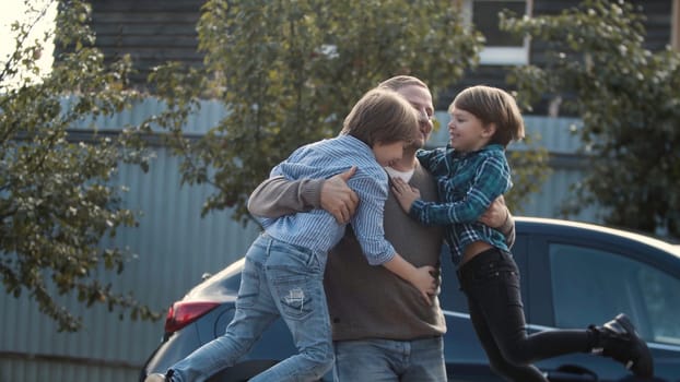 Father meets his little boys near his car outdoors. Stock. Concept of happy family and fatherhood.