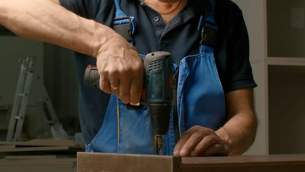 Close up of a man carpenter using screwdriver while working with a wooden product. Creative. Woodwork at the workshop.
