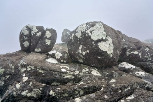 Large boulders covered with lichen spots on foggy morning. Typical scenery during trek to Pic Boby aka Imarivolanitra in Andringitra National Park, highest accessible  peak of Madagascar