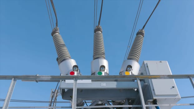 Electric transformer at substation. Action. Gas tank switch on electric transformer substation. Highly conductive equipment on background of blue sky