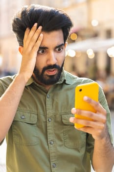 Surprised young adult man use smartphone loses, bad news, fortune loss, fail outdoors in city street