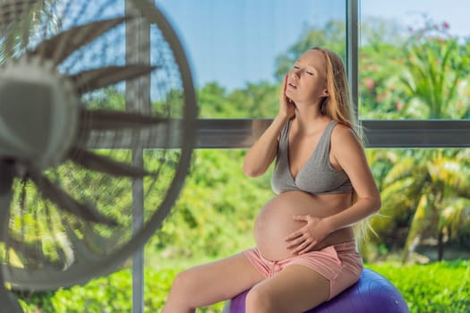 A pregnant woman seeks relief from an abnormal heatwave by using a fan, ensuring her comfort and well-being during sweltering conditions