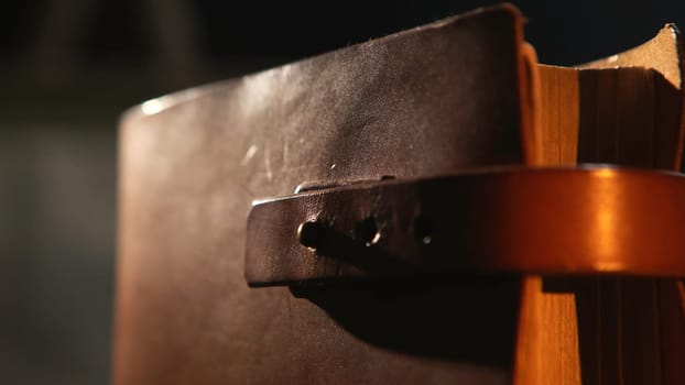 Vintage books with leather bound, close-up. Stock footage. Close-up of old leather bound book with the leather straps in the dark room.