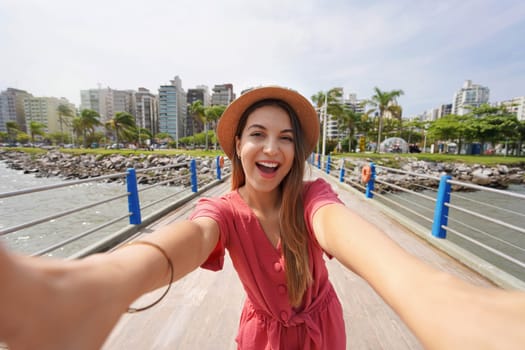 Selfie girl in Floripa. Happy laughing fashion woman takes self portrait in the city of Florianopolis, Santa Catarina, Brazil.