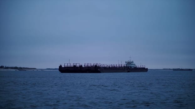 Huge floating vessels in inclement weather. Clip. The navy sails in the winter against the background of the blue sky.