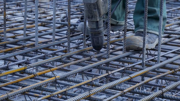 Construction worker. Worker in the construction site making reinforcement metal framework for concrete pouring