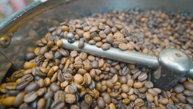 Close-up of coffee beans stirred and roasted. Action. Special machine mixes coffee beans for thermal processing. Roasting coffee in machine