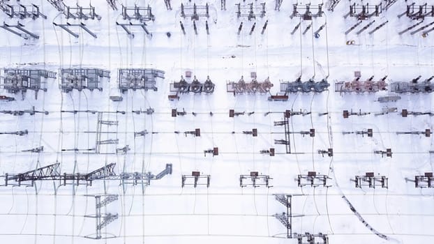 Rows of electric poles. Action. Top view of electrical substation with rows of transformers in winter. Powerful electrical substation with new equipment in winter. Electric power industry