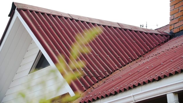 Corrugated roofing roof. Stock footage. Details of red roof made and covered from metal profile. Close-up of roof covering from slopes of side windows