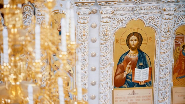 Christian orthodox church interior in white and golden colors. Video. Chandelier with artificial candles in the temple with iconostasis.