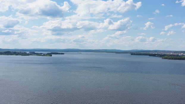 Top view of beautiful lake on background of horizon with sky. Video. Panorama of clear lake and green shores with beautiful horizon of blue sky