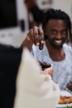 African American Muslim man delicately takes dates to break his fast during the Ramadan month, seated at the family dinner table, embodying a scene of spiritual reflection, cultural tradition, and the shared anticipation of the communal iftar