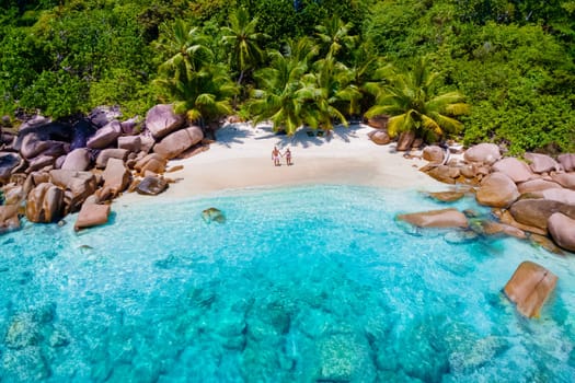 Praslin Seychelles tropical island with withe beaches and palm trees, couple men and women mid age on vacation at the Seychelles visiting the tropical beach of Anse Lazio Praslin Seychelles drone view