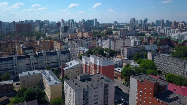 A summer sunny city taken from a bird's-eye view. Clip. A small provincial town in the summer with residential buildings, parks and parking lots for cars.