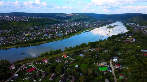 Arial view of a small town crossed by a river with a bridge. Clip. Ecological place, living in the countryside.