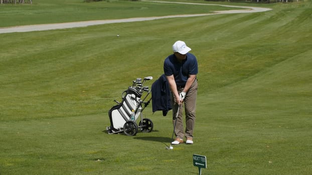 Golfers hit sweeping golf course in the summer. The game of Golf