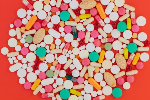 Medical background with pills and capsule on red background.Assorted pharmaceutical medicine pills, tablet. Heap of various assorted medicine tablets and pills different colors. Health care. Top view