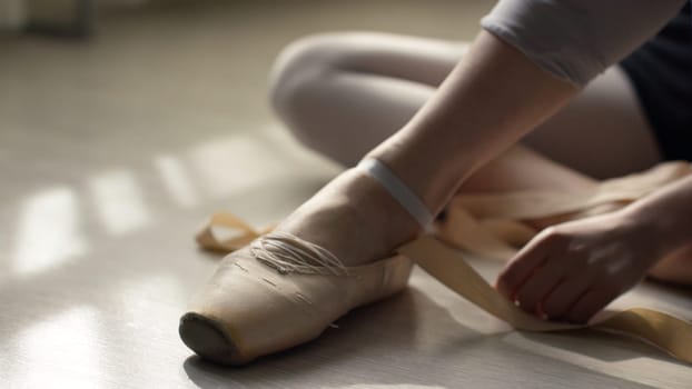 ballet dancer tie up her pointes. Ballet dancer tying ballet shoes before training