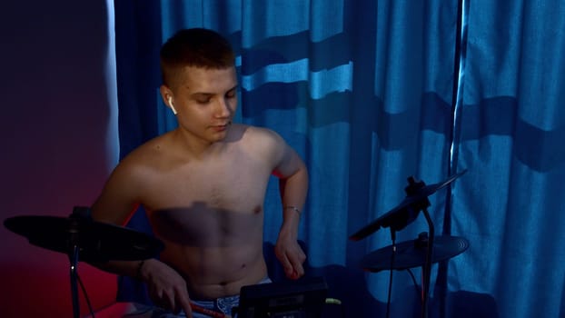 A young caucasian man drummer plays a drum kit in a music studio. Media. Creating music and art, rock band member is rehearsing, studying.