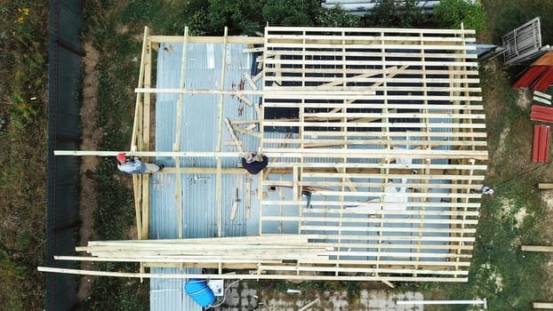 Aerial view of two senior men building a wooden frame house in the summer on their own location. Stock footage. Construction workers with a drills