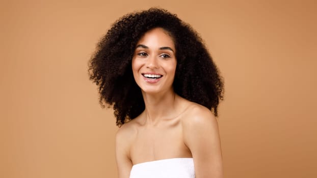 Natural beauty. Happy young latin lady with curly hair enjoying selfcare routine, posing over brown background, panorama
