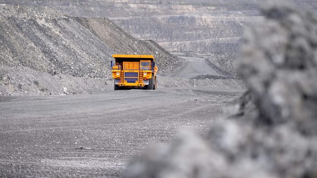 Truck driving career on road. Dump truck carries ore mined in open pit. Heavy large transport in mining industry on background of open white multistage quarry