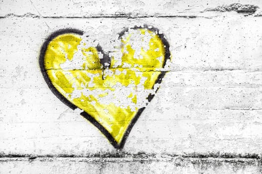 Painted yellow abstract heart shape love symbol, dirty wall background, metaphor to urban and romantic valentine, grunge style.