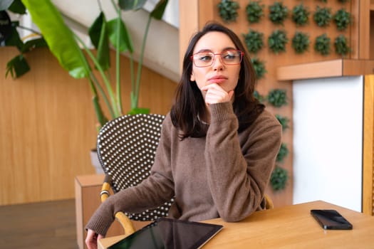 Business woman wear glasses sitting at desk thinking and looking away
