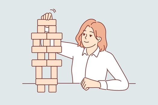 Business woman builds tower of wooden cubes, symbolizing sustainable business strategy
