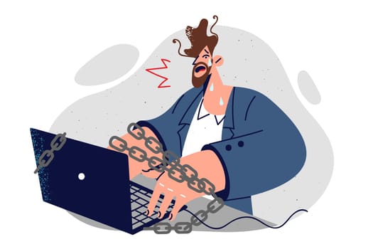 Corporate slave is crying sitting at computer with chains and feeling tired or professional burnout