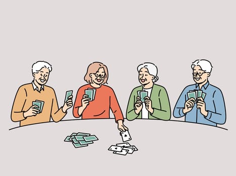 Old men and women play cards having fun after retirement and enjoying socializing with friends