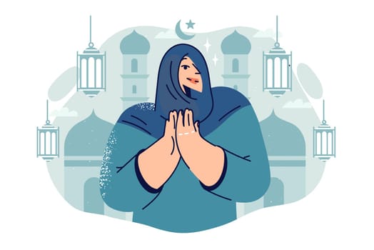 Arab woman prays standing near mosque and turns to allah for blessings during ramadan