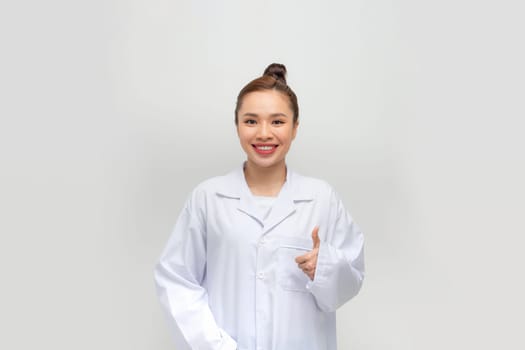 Photo of cute charming woman doc dressed white coat pointing thumb up 