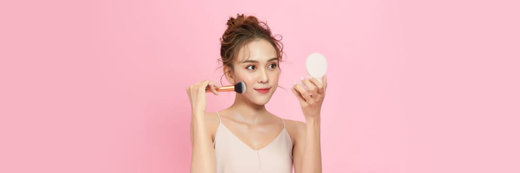 Young woman applying make-up from powder compact.