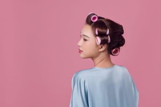 Portrait of beautiful woman with hair curlers posing isolated