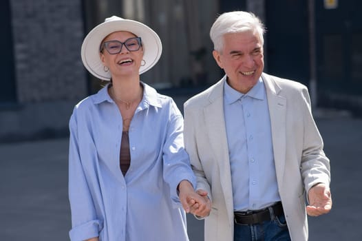 Stylish elderly laughing couple on a walk. Romantic relationships of mature people.