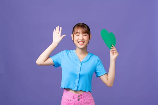 Sweet adorable lady wear blue crop top holding green heart isolated purple background