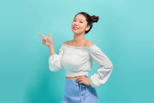 Teenager girl over isolated blue background pointing finger to the side