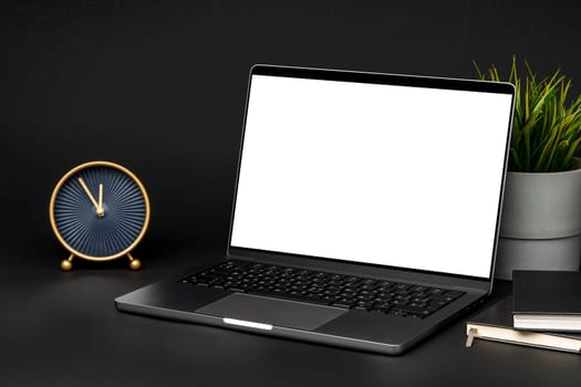 Laptop with blank screen on table against black background